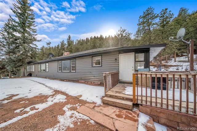 snow covered house with a chimney and a wooden deck