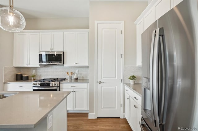 5930 S Platte Canyon Dr, Littleton, CO 80123 - kitchen with appliances with stainless steel finishes, tasteful backsplash, wood finished floors, white cabinetry, and decorative light fixtures