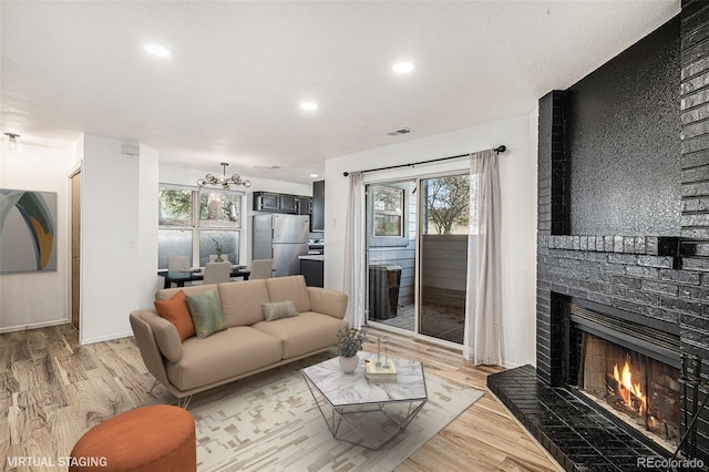 8035 W Eastman Pl Unit 106, Lakewood, CO 80227 - living area featuring light wood-style floors, a fireplace, a chandelier, recessed lighting, and baseboards