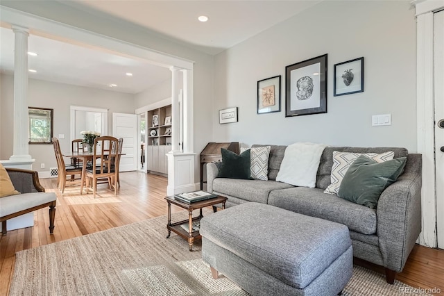 living room with built in features, wood-type flooring, and ornate columns