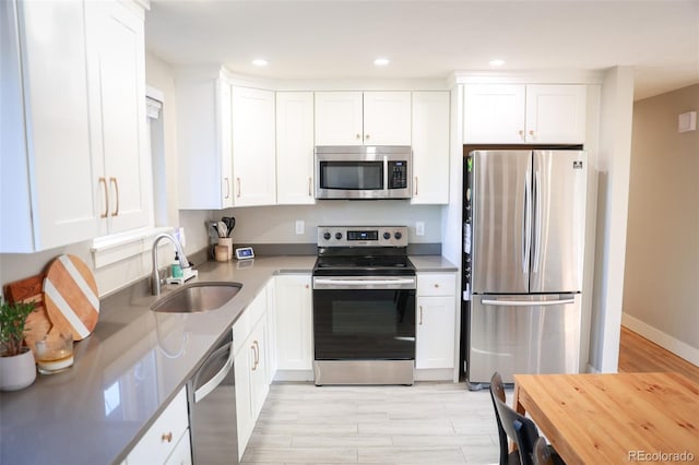 7100 Saulsbury St, Arvada, CO 80003 - kitchen with appliances with stainless steel finishes, a sink, white cabinetry, recessed lighting, and light wood-style flooring