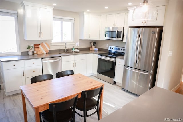 7100 Saulsbury St, Arvada, CO 80003 - kitchen featuring stainless steel appliances, a sink, white cabinets, recessed lighting, and light wood-type flooring