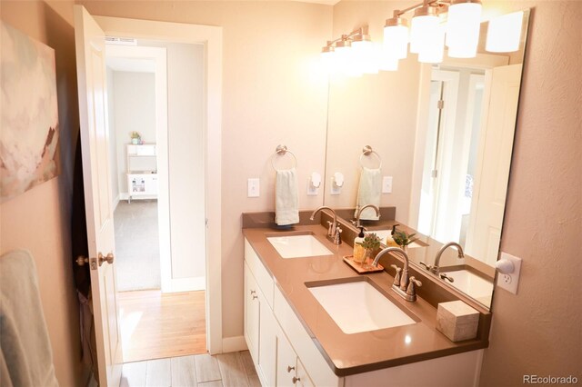 7100 Saulsbury St, Arvada, CO 80003 - bathroom featuring double vanity, baseboards, and wood finished floors