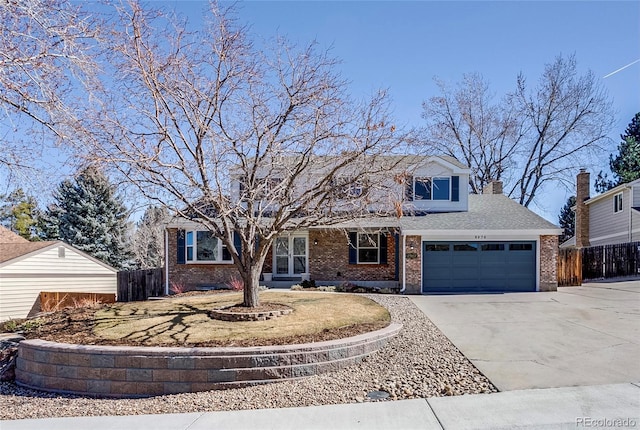 traditional home with brick siding, a shingled roof, concrete driveway, an attached garage, and fence