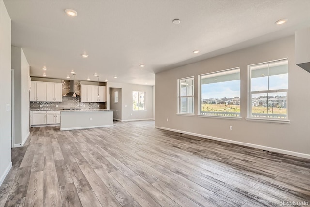 unfurnished living room featuring light wood-type flooring and sink