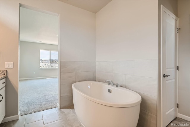 bathroom featuring tile patterned flooring, vanity, tile walls, and a washtub