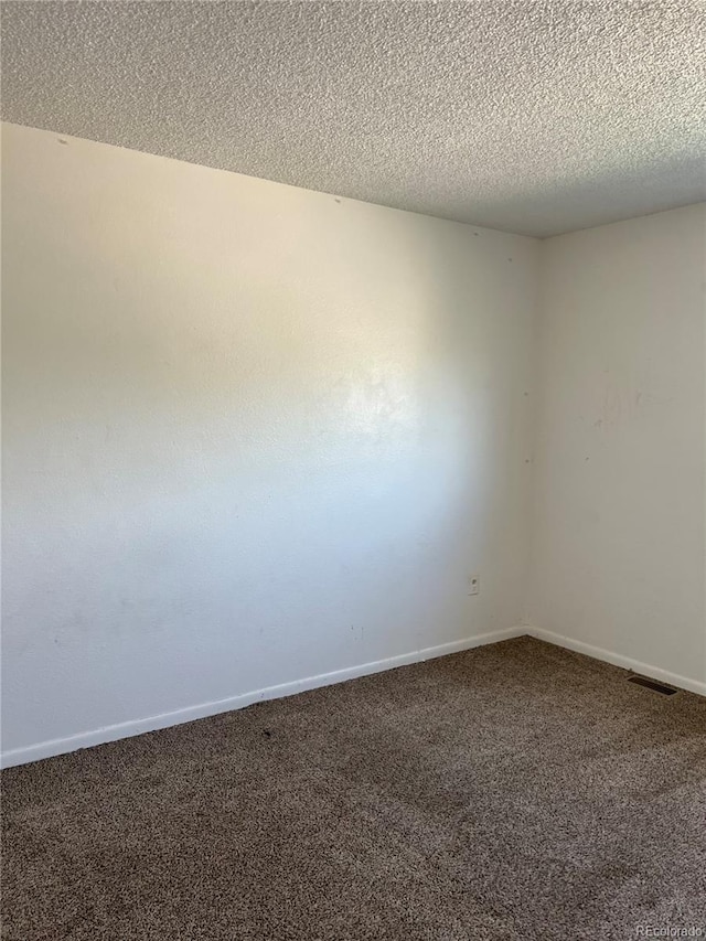 carpeted empty room with a textured ceiling