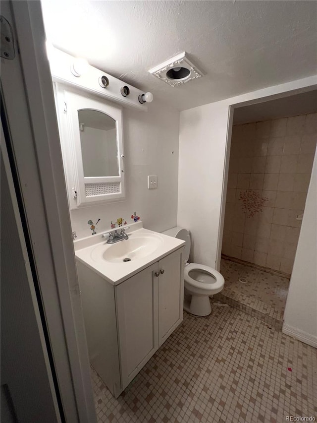 bathroom with vanity, a textured ceiling, and toilet