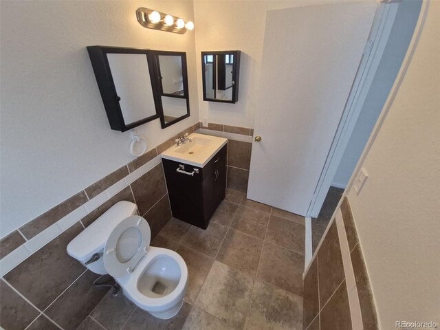 14190 E Gunnison Pl, Aurora, CO 80012 - bathroom featuring tile walls, vanity, toilet, a wainscoted wall, and tile patterned floors