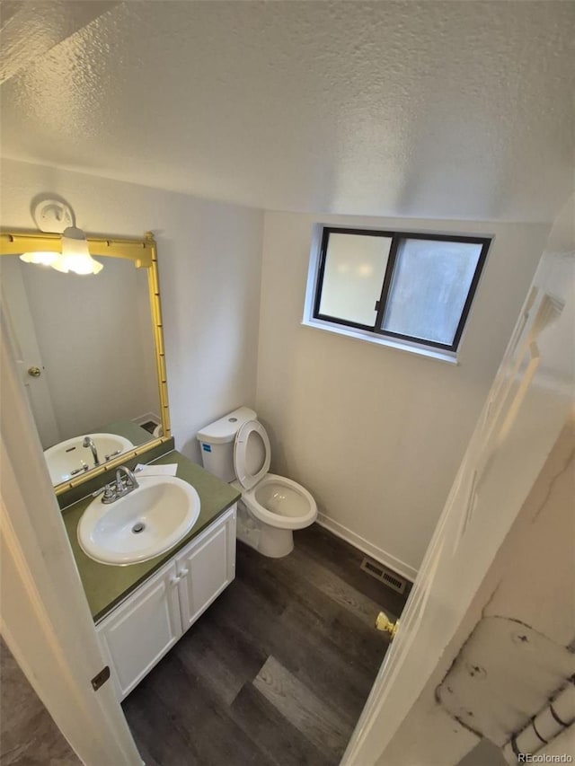 14190 E Gunnison Pl, Aurora, CO 80012 - bathroom featuring a textured ceiling, toilet, wood finished floors, and vanity