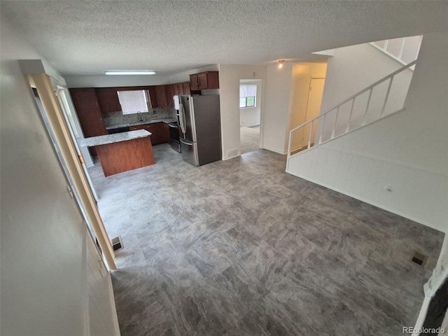 14190 E Gunnison Pl, Aurora, CO 80012 - kitchen with stainless steel refrigerator with ice dispenser, a textured ceiling, tasteful backsplash, open floor plan, and a sink