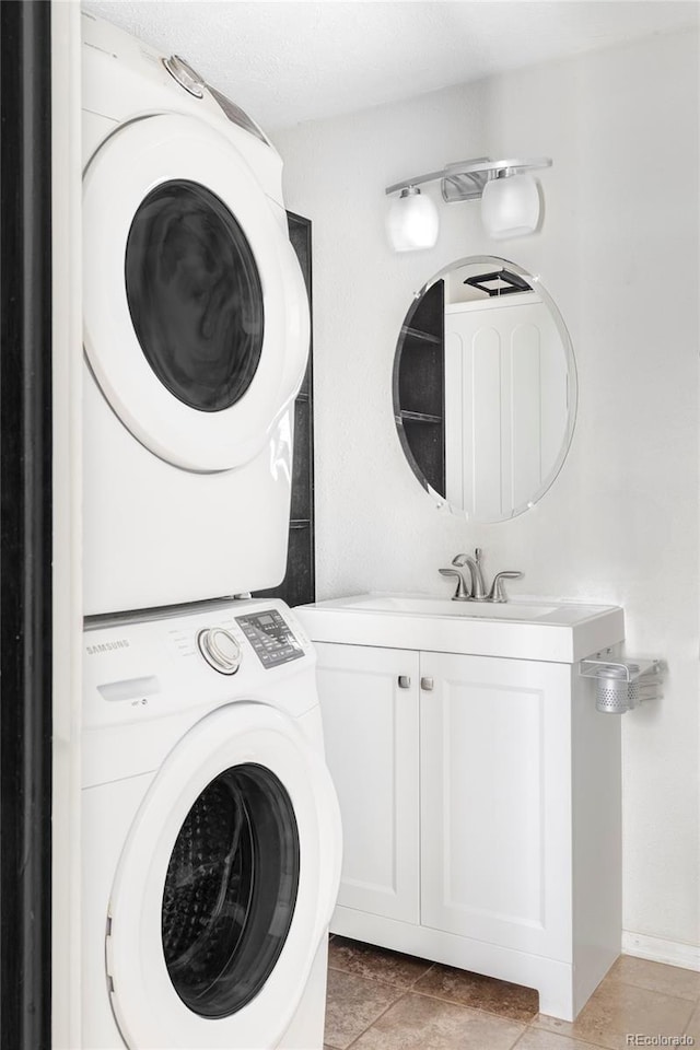 laundry area with a sink, cabinet space, and stacked washer and clothes dryer