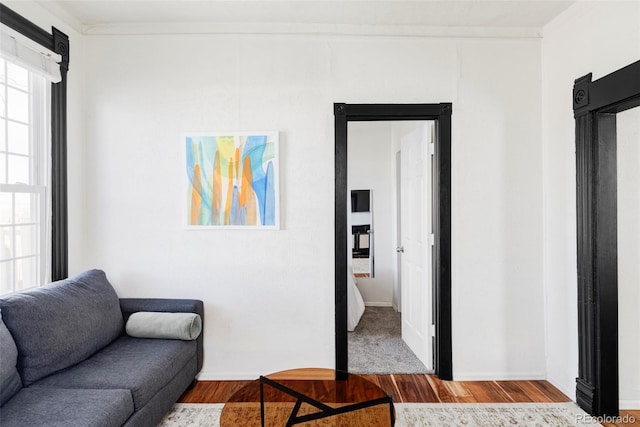 living area with baseboards, wood finished floors, and ornamental molding