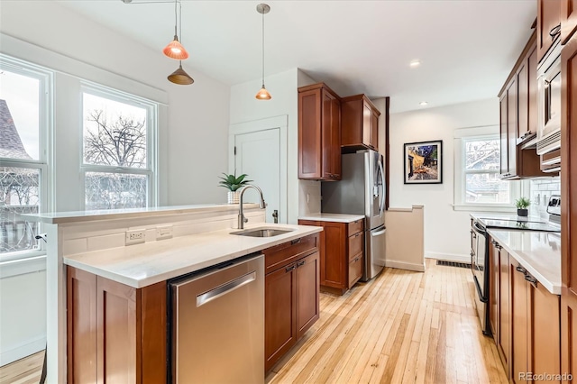 kitchen with light wood finished floors, stainless steel appliances, light countertops, and a sink