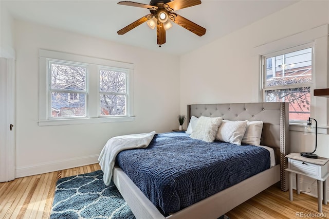 bedroom with baseboards, wood finished floors, ceiling fan, and multiple windows