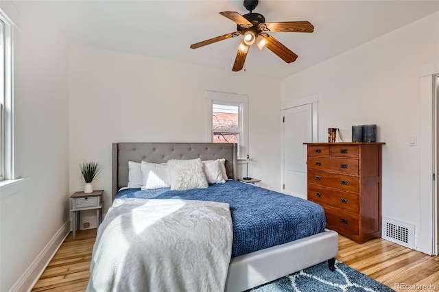 bedroom featuring light wood finished floors, baseboards, visible vents, and ceiling fan