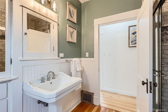 bathroom with wainscoting, wood finished floors, and visible vents