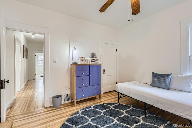 bedroom featuring baseboards, a ceiling fan, visible vents, and light wood-style flooring