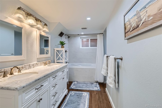 full bath featuring tiled shower / bath combo, wood finished floors, a sink, and visible vents