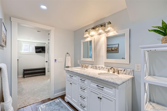 bathroom featuring baseboards, wood finished floors, a sink, and double vanity
