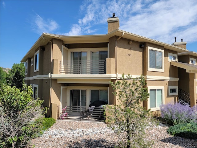 1965 Montura Vw Unit 204, Colorado Springs, CO 80919 - rear view of house with a balcony, a chimney, and stucco siding