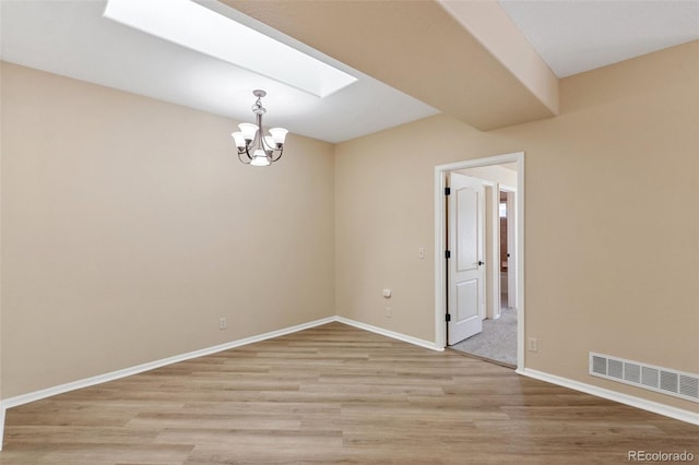 1965 Montura Vw Unit 204, Colorado Springs, CO 80919 - spare room featuring an inviting chandelier, light wood-style flooring, visible vents, a skylight, and baseboards