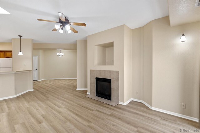 1965 Montura Vw Unit 204, Colorado Springs, CO 80919 - unfurnished living room featuring ceiling fan with notable chandelier, light wood-type flooring, visible vents, a tiled fireplace, and baseboards