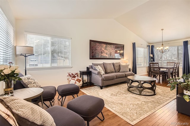 living room featuring a notable chandelier, wood-type flooring, and lofted ceiling