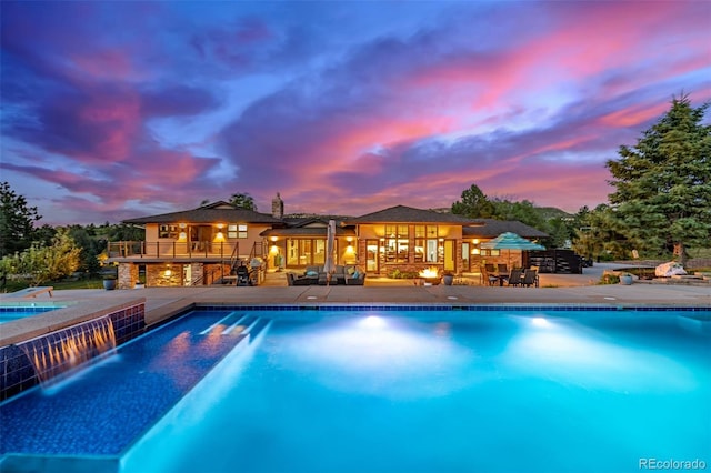 5727 Colorow Dr, Morrison, CO 80465 - pool at dusk featuring an outdoor pool and a patio area