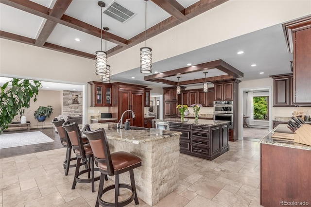 5727 Colorow Dr, Morrison, CO 80465 - kitchen with a kitchen island with sink, double oven, coffered ceiling, beamed ceiling, and light stone countertops