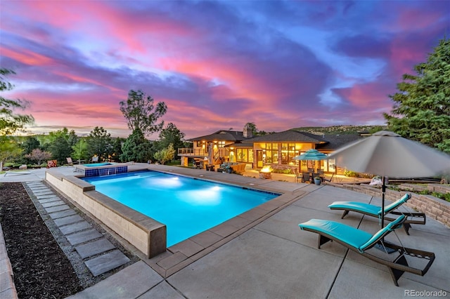 5727 Colorow Dr, Morrison, CO 80465 - pool at dusk featuring an in-ground hot tub, a patio area, and an outdoor pool
