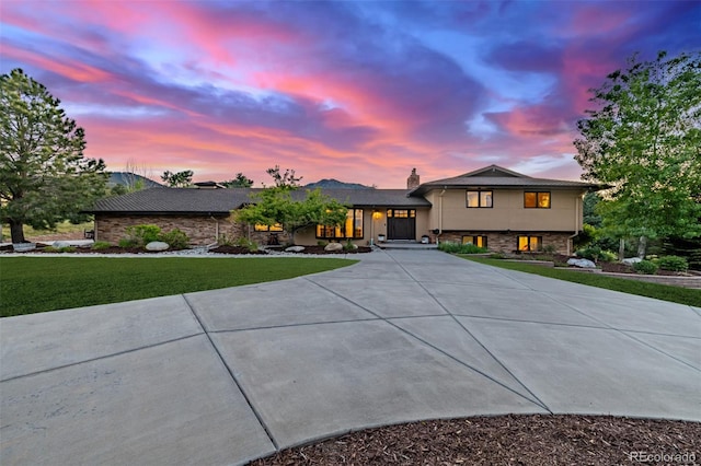 5727 Colorow Dr, Morrison, CO 80465 - tri-level home featuring curved driveway, a yard, stone siding, and a chimney