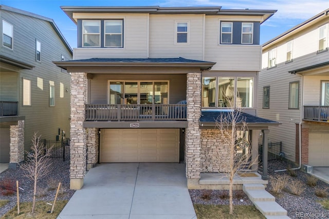 view of front of property with stone siding, a balcony, concrete driveway, and an attached garage