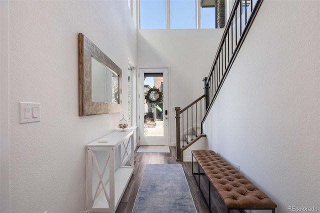 entryway with stairway, dark wood finished floors, and a towering ceiling