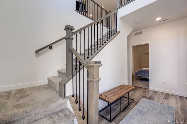 stairway with visible vents, baseboards, and wood finished floors