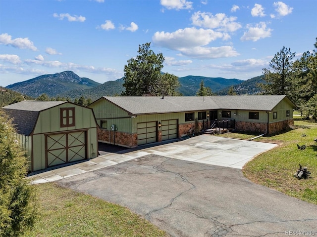 view of front of house featuring a storage shed, a mountain view, a garage, and aphalt driveway