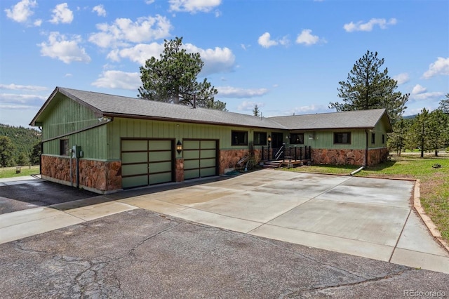 ranch-style home featuring an attached garage, driveway, and stone siding