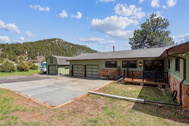 exterior space with concrete driveway, a shingled roof, a mountain view, and a garage