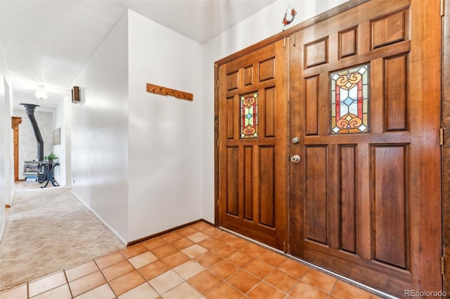 foyer with baseboards, light carpet, light tile patterned floors, and a wood stove