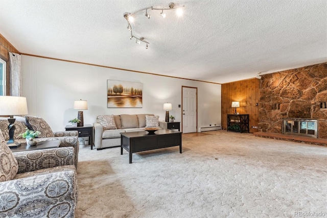 living room featuring wooden walls, carpet flooring, baseboard heating, a textured ceiling, and ornamental molding