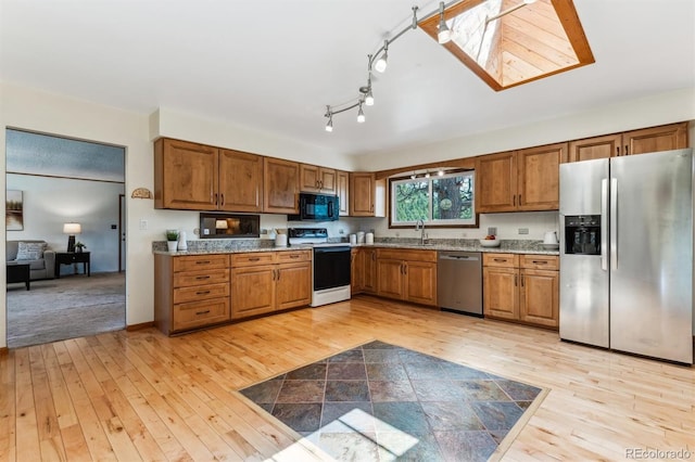 kitchen featuring a sink, light wood finished floors, brown cabinets, and stainless steel appliances