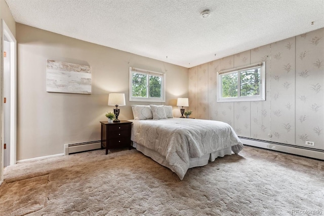 carpeted bedroom with a textured ceiling, baseboard heating, and multiple windows