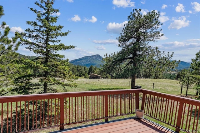 wooden terrace featuring a lawn and a mountain view