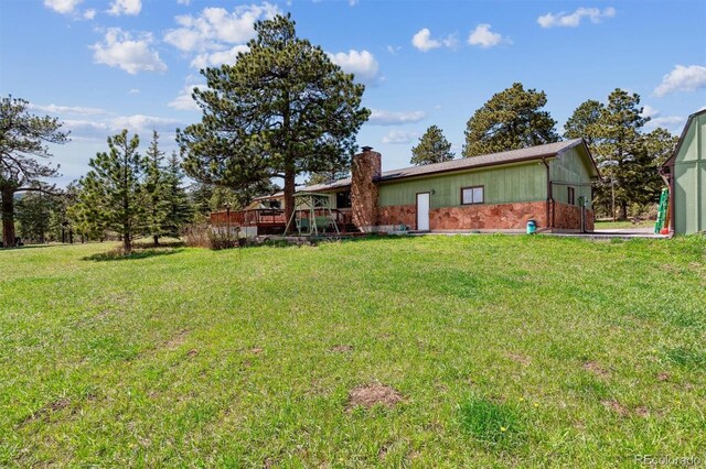 back of property featuring a lawn, a chimney, and a wooden deck