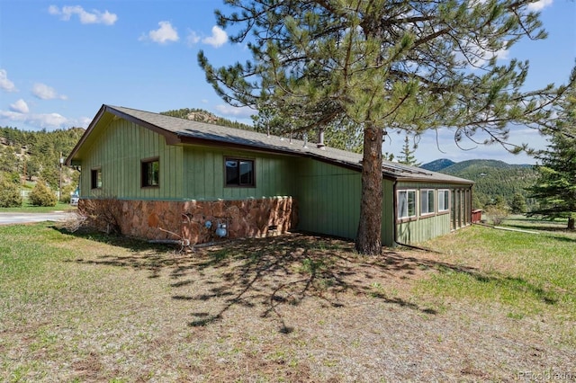 view of home's exterior with a lawn and a mountain view