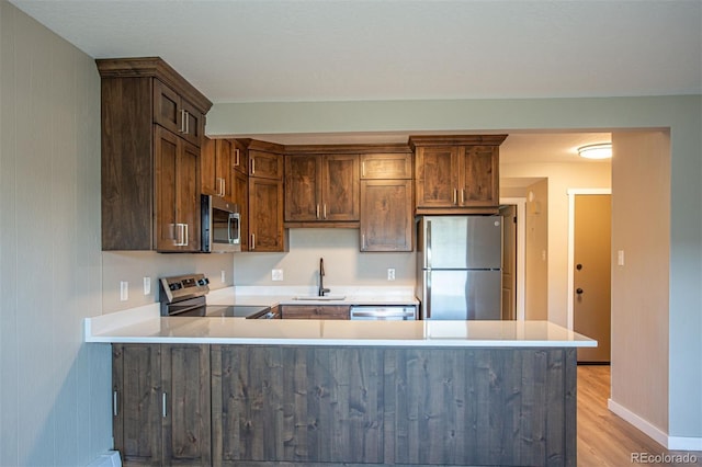 1153 Straight Creek Dr Unit F102, Dillon, CO 80435 - kitchen with stainless steel appliances, a sink, light countertops, a peninsula, and light wood-type flooring