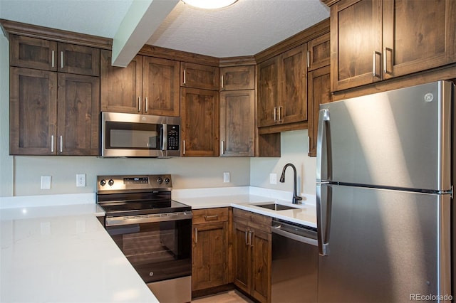 1153 Straight Creek Dr Unit F102, Dillon, CO 80435 - kitchen featuring appliances with stainless steel finishes, a sink, light countertops, beam ceiling, and dark brown cabinetry