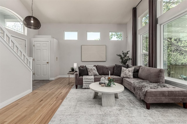 living area featuring wood finished floors, stairs, plenty of natural light, and baseboards
