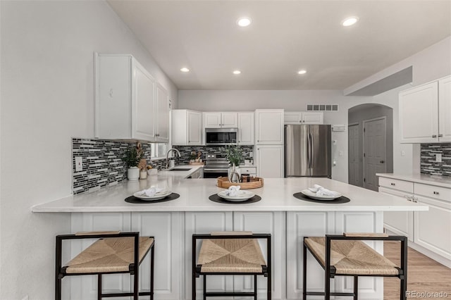 kitchen featuring stainless steel appliances, tasteful backsplash, a sink, light countertops, and recessed lighting