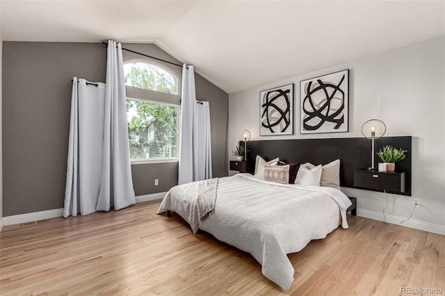 bedroom with light wood finished floors, lofted ceiling, and baseboards